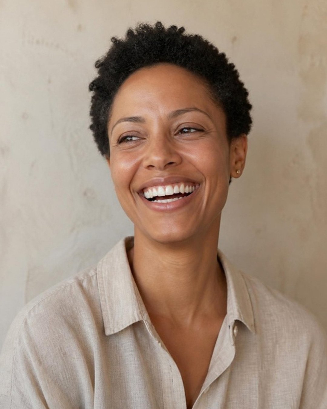Woman in her thirties laughing, in soft natural light.